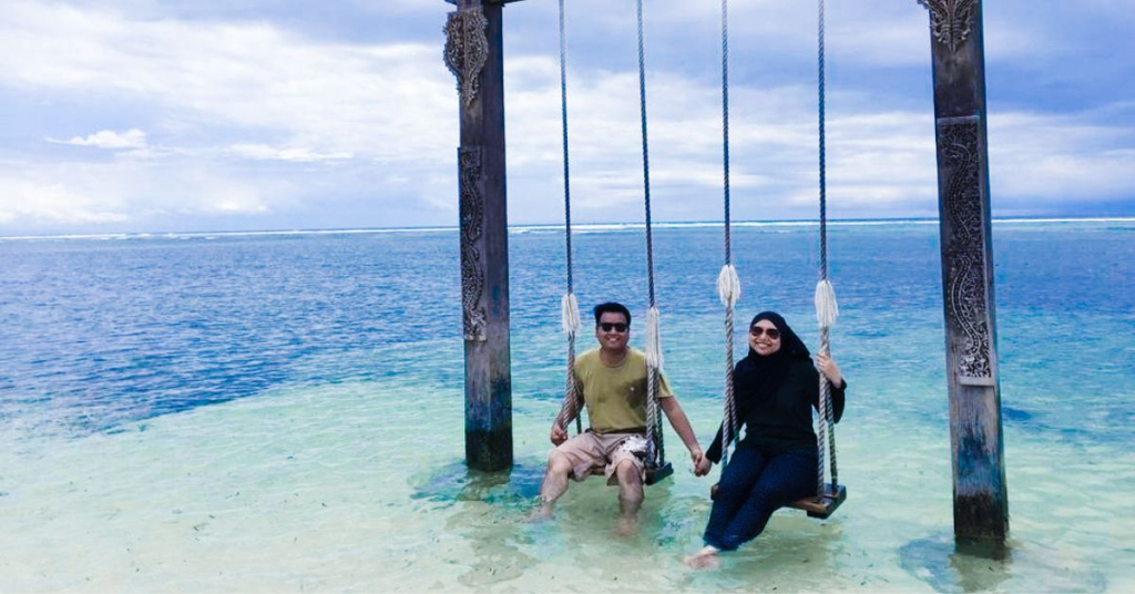 Pasangan menikmati ayunan laut di Gili Trawangan saat paket wisata Lombok 5 hari 4 malam