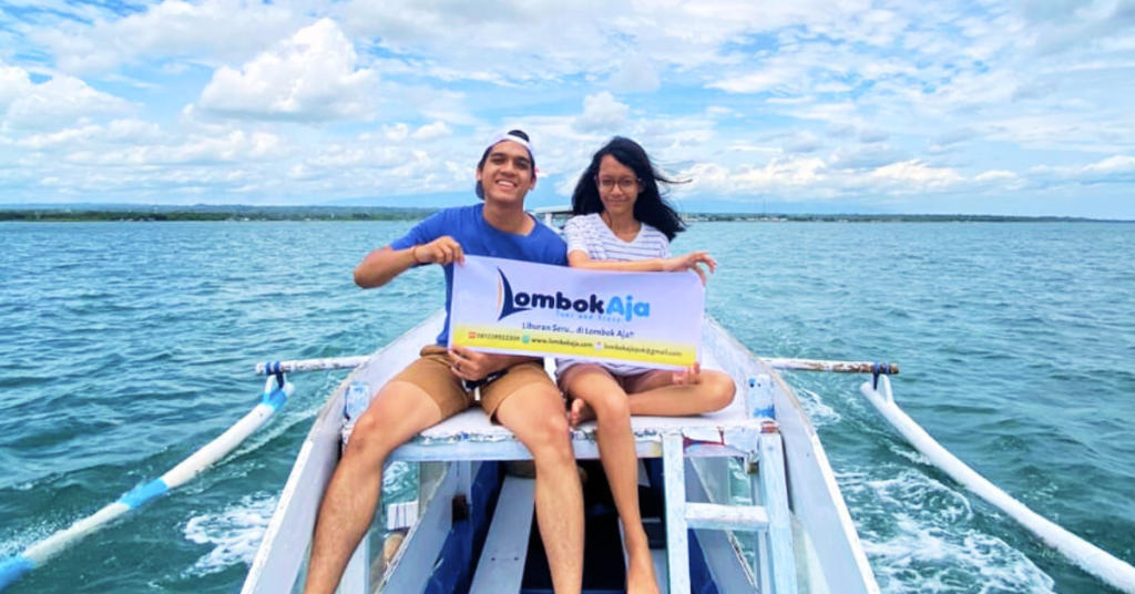 Pasangan wisatawan menaiki perahu saat menikmati Paket Explore Lombok 4 Hari