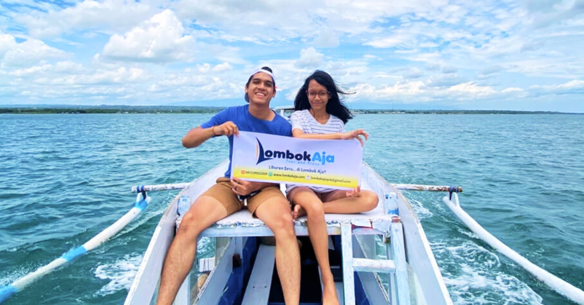Pasangan wisatawan menaiki perahu saat menikmati Paket Explore Lombok 4 Hari