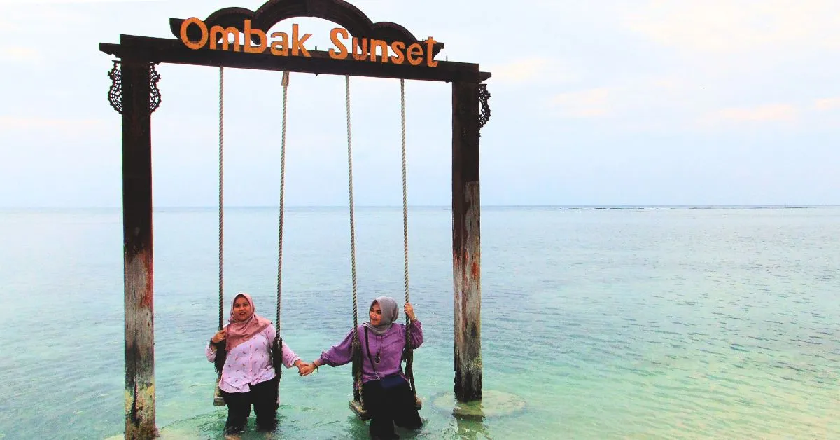 Dua wisatawan berpose di ayunan ikonik Ombak Sunset Gili Trawangan dalam Program Tour Lombok Opsi C