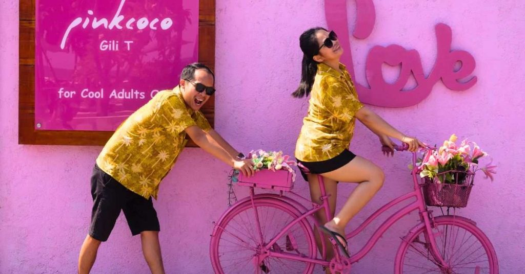 Pasangan mengenakan baju kuning senada berpose romantis dengan sepeda pink di PinkCoco Gili T, Lombok