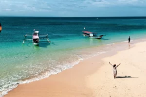 Suasana wisatawan menikmati keindahan laut jernih dan pasir merah muda saat explore Pantai Pink di Lombok.